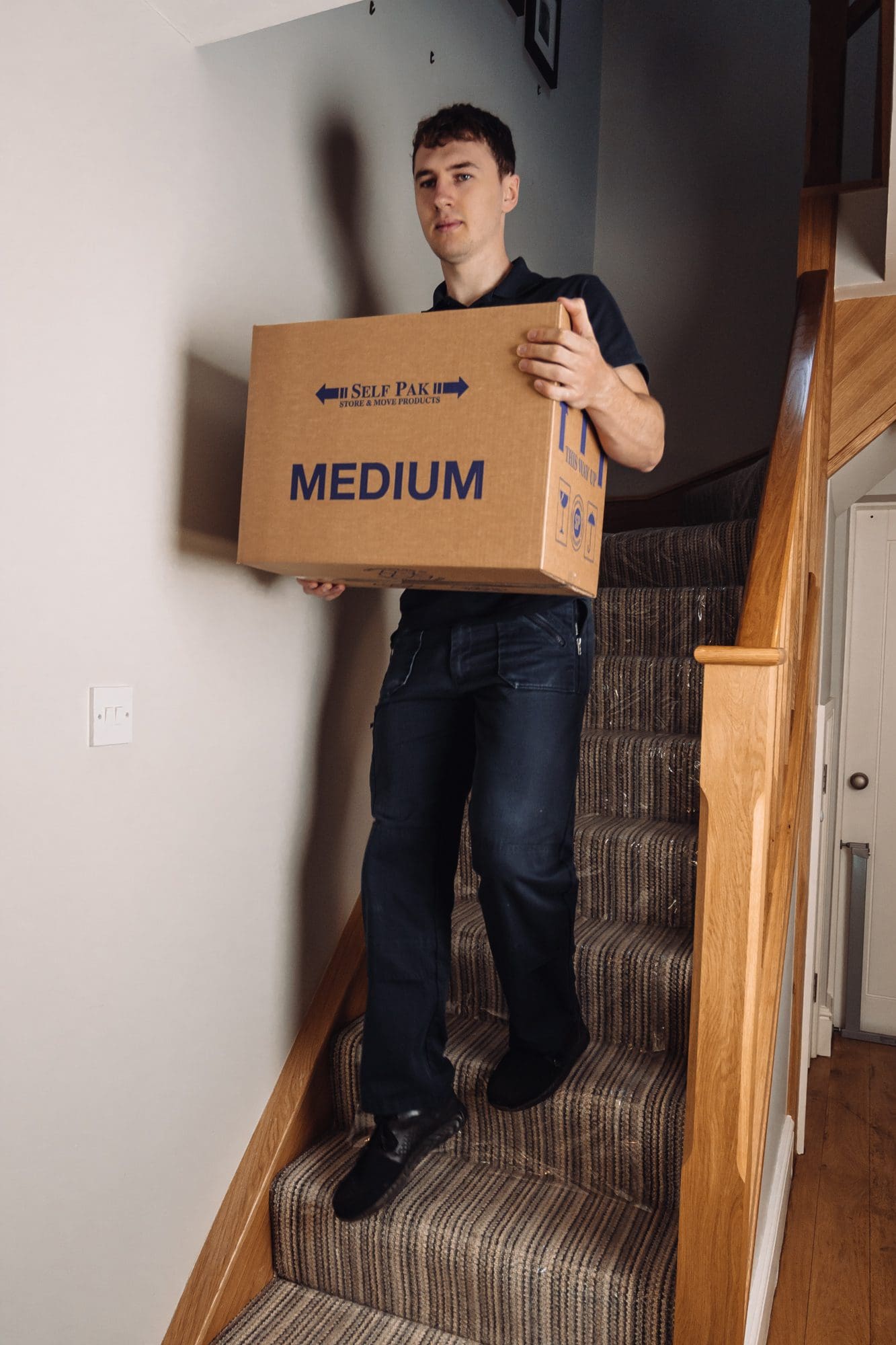 a man going down on a stairs carrying one box